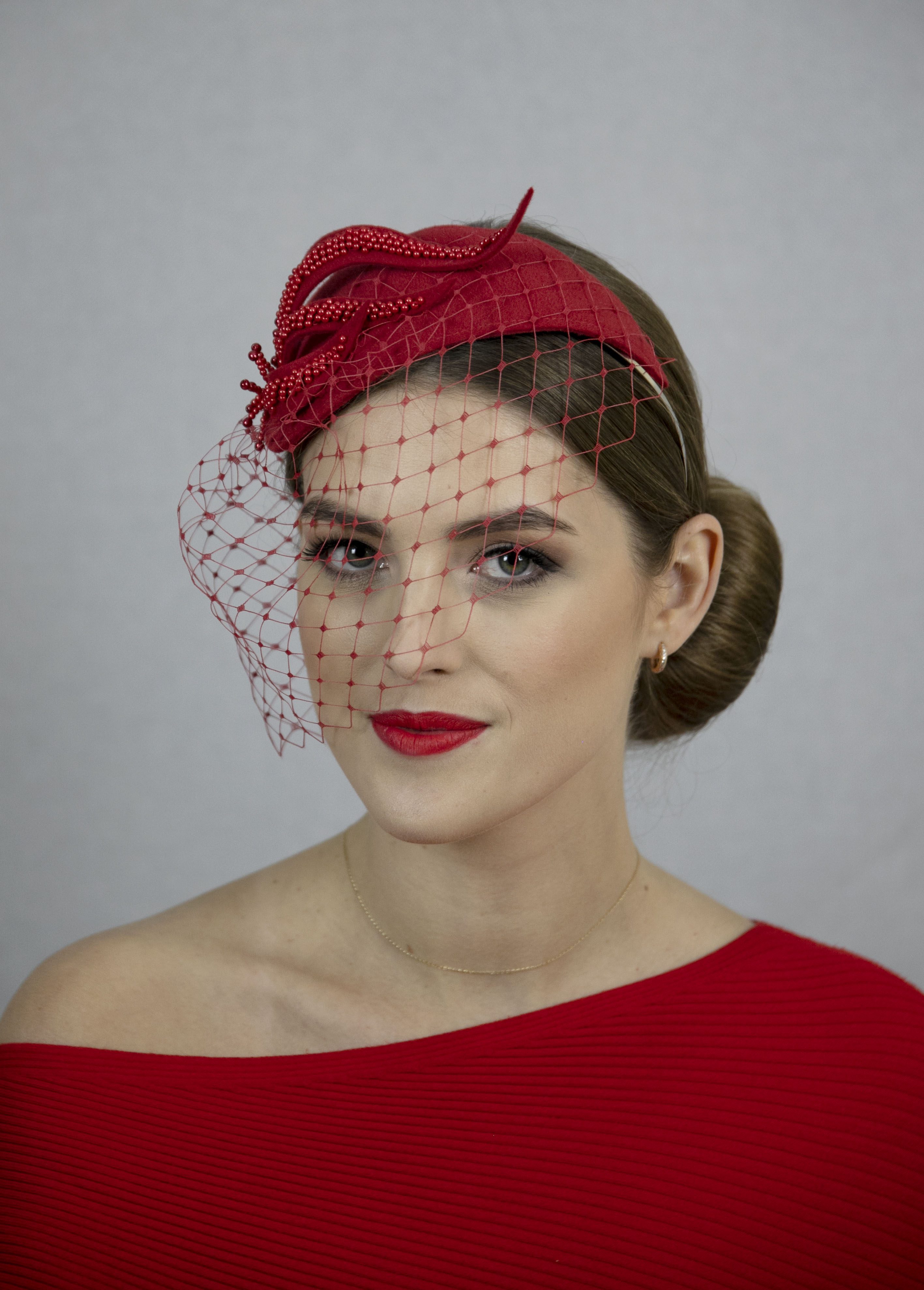 Red fascinator hat with short net.